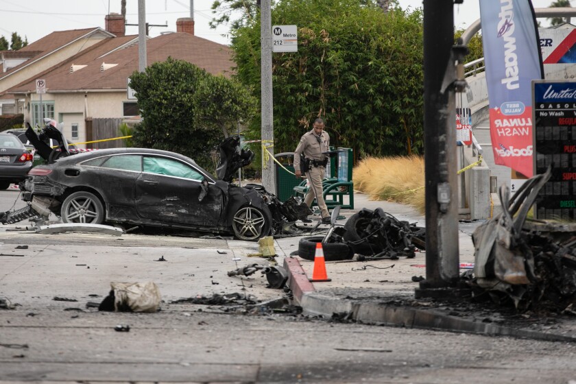 A CHP officer walks past a burnt out wreckage of vehicles near a gas station after an accident